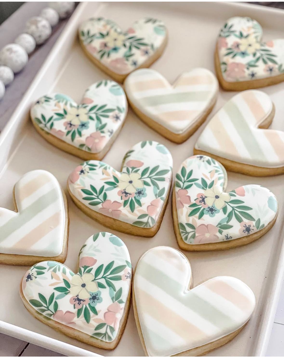 Floral and striped heart sugar cookies arranged on a white tray